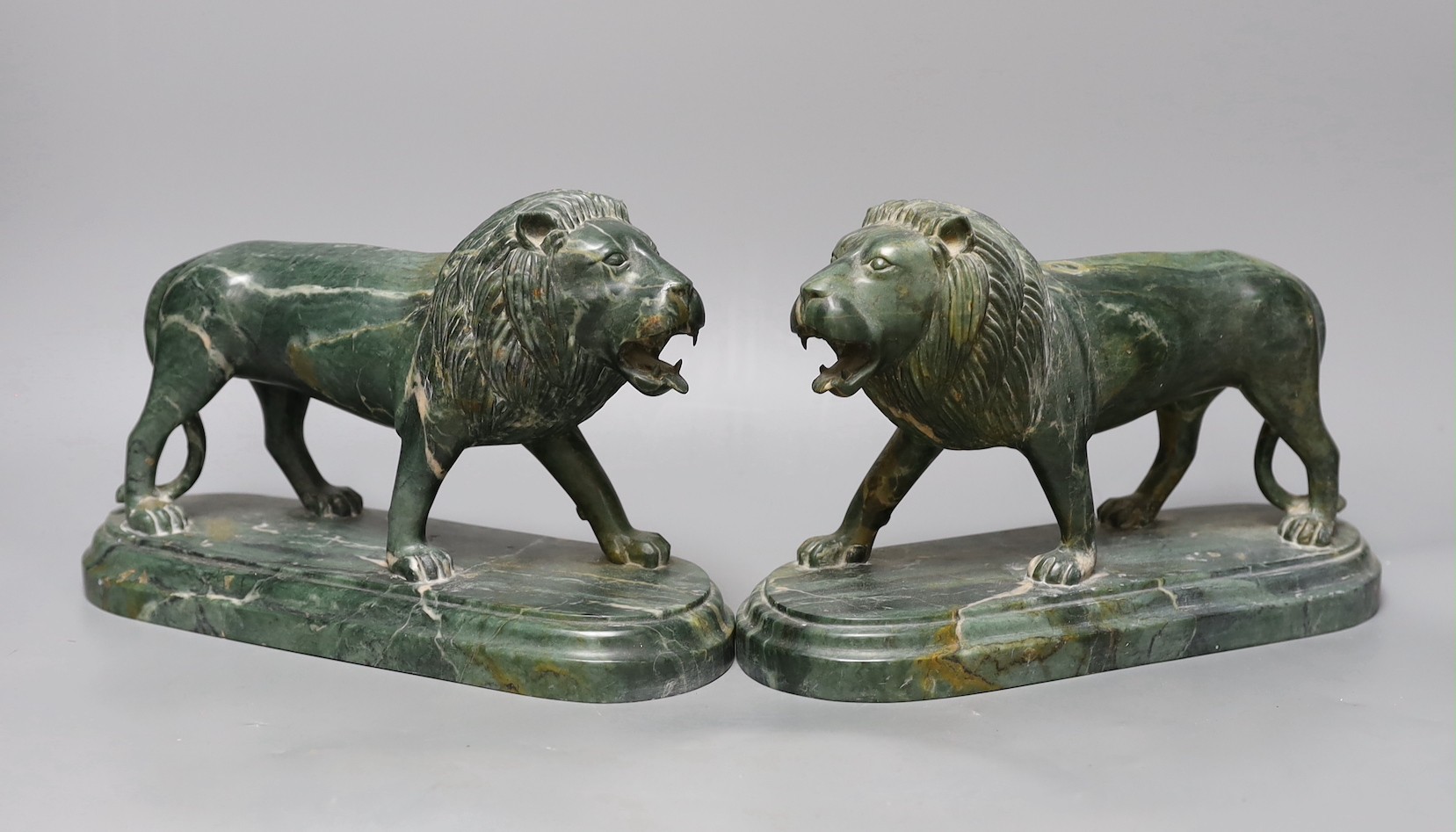 A pair of carved green serpentine models of lions rampant, 24 cms wide